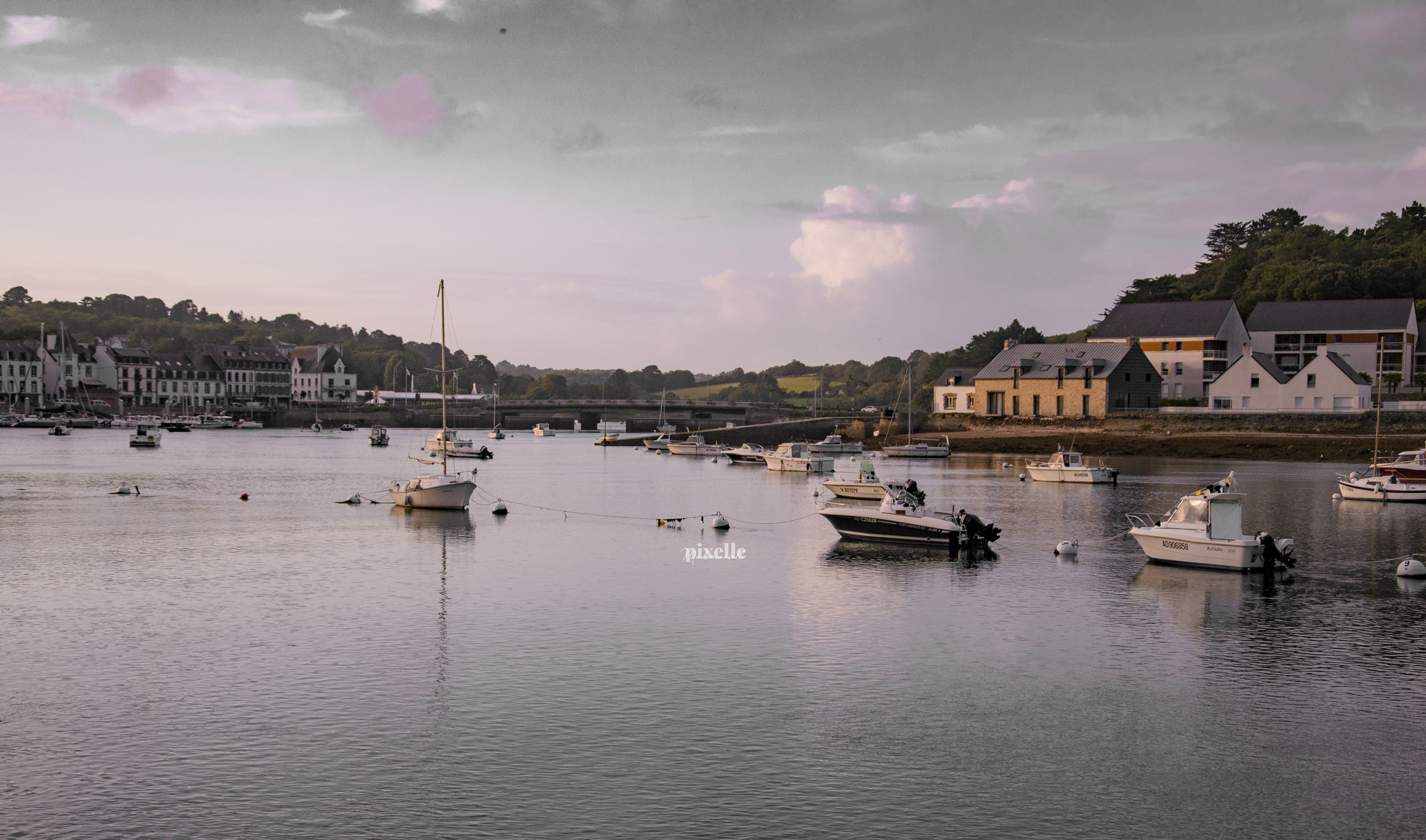 Photo d'un port breton : de jolies maison à toits d'ardoise, quelques petits batons, un ciel gris teinté de rose qui se reflette dans l'eau à marée haute ou en tout cas pas basse